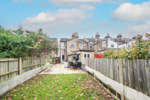 a backyard with a fence and houses in the background at Lovely 2BR house in Norwood Junction London in London