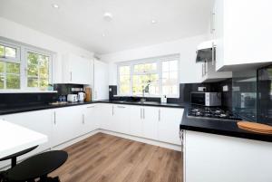 a kitchen with white cabinets and black counter tops at Stylish 2BR Oasis Steps from Wembley Stadium in London