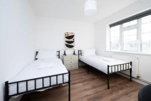 1 dormitorio con 2 camas y ventana en Stylish 2BR Oasis Steps from Wembley Stadium en Londres