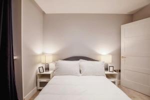 a bedroom with a large white bed with two lamps at Modern 2BR London Flat Style and Comfort Combined in London