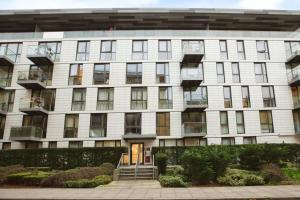 a large white building with windows and bushes at Modern 2BR London Flat Style and Comfort Combined in London