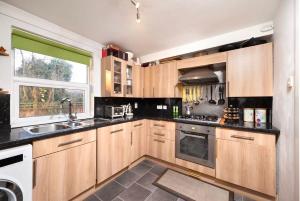 een keuken met houten kasten, een wastafel en een raam bij Charming 1BR flat with patio perfect for couples in Londen