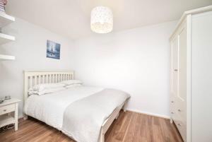 a bedroom with a white bed and a wooden floor at Charming 1BR flat with patio perfect for couples in London