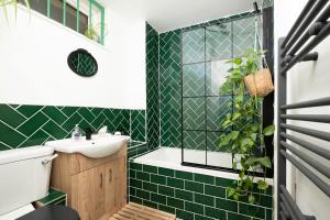 a bathroom with green tiled walls and a sink at Cozy 1-Bedroom Oasis with Balcony in London's Heart in London