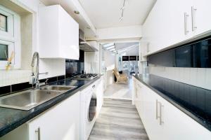 達格納姆的住宿－Chic 4BR Home with Ensuite bath and Cozy Garden，白色的厨房配有水槽和洗碗机
