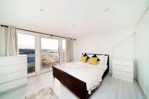 een slaapkamer met een groot bed met gele kussens bij Chic 4BR Home with Ensuite bath and Cozy Garden in Dagenham