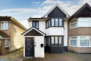 a white and black house with a black door at Chic 4BR Home with Ensuite bath and Cozy Garden in Dagenham
