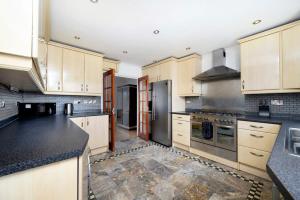 a kitchen with white cabinets and black counter tops at Chic 2BR Home - Eats and Sights Closeby in London