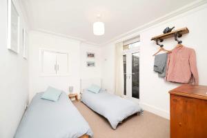 1 dormitorio con 2 camas, vestidor y ventana en Charming 2BR Home with Garden, en Twickenham