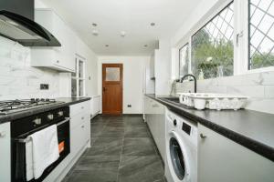 a white kitchen with a sink and a stove at Charming 3BR House With Free Parking and Garden in Hounslow