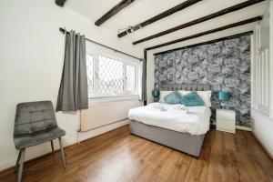 a bedroom with a bed and a chair in it at Charming 3BR House With Free Parking and Garden in Hounslow