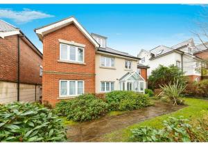 a brick house with white windows and bushes at Chic Croydon 2BR Flat - Free Parking in Purley