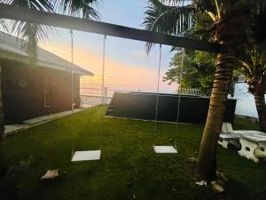 a swing in a yard with a palm tree at Seaview Mini Chalet by StayCo - DIRECT BEACH ACCESS in Tanjung Bungah