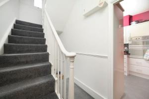 a staircase in a home with white walls and grey carpet at Chic and comfortable London 2BR home in London