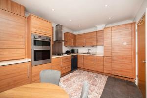 a kitchen with wooden cabinets and a wooden table at Chic and Spacious 3BR Family Home with Garden in Northolt