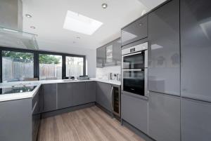 een keuken met witte apparatuur en een groot raam bij Charming 3BR House with Garden in Uxbridge