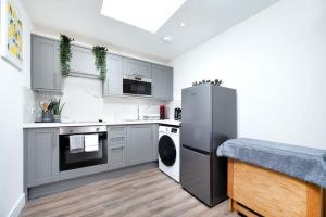 a kitchen with a refrigerator and a dishwasher at Cozy single level flat with parking in Enfield