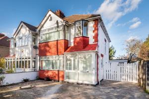 a large house with a white fence at Cozy single level flat with parking in Enfield