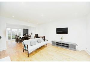uma sala de estar branca com um sofá branco e uma televisão em 5BR Family Home close to Parks and City Links em Purley