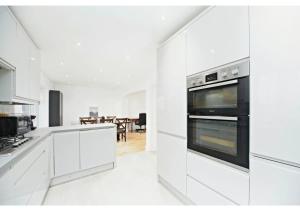 a white kitchen with white cabinets and appliances at 5BR Family Home close to Parks and City Links in Purley