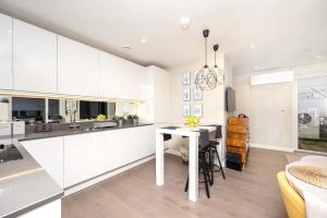 a kitchen with white cabinets and a white table at Stunning 2BR Apt Bromley Views Terrace in Bromley