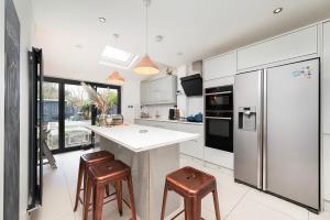 a kitchen with a refrigerator and two bar stools at Charming 2BR House with Garden in Shepperton