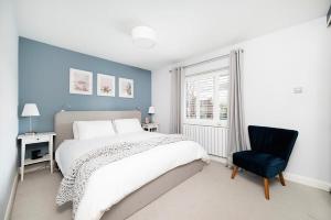 a bedroom with a bed and a chair and a window at Charming 2BR House with Garden in Shepperton