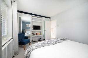 - une chambre blanche avec un lit et une chaise bleue dans l'établissement Charming 2BR House with Garden, à Shepperton