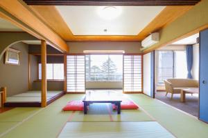 Habitación con mesa y algunas ventanas. en Ooedo Onsen Monogatari Premium Yamashitaya, en Kaga