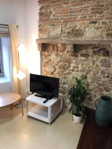 sala de estar con TV y pared de piedra. en Apartamento 1 Penedo en Sintra