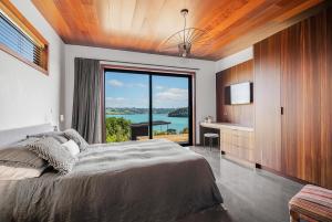 ein Schlafzimmer mit einem großen Bett und einem großen Fenster in der Unterkunft Nook Bay House in Whangarei