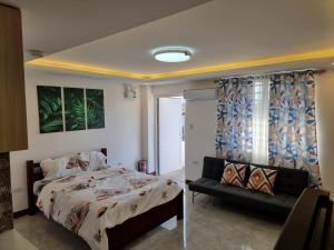 1 dormitorio con cama y sofá en Mary Ann Gurel, Amaya 2 Tanza Cavite Staycation, Transient, Short Term,Long Term, Condo Type with own Balcony., en Tanza