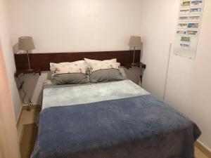 Apartamento 1 Penedo في سينترا: سرير مع وسادتين وبطانية زرقاء
