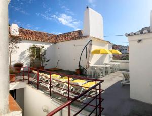 einen Balkon mit Stühlen und Tischen auf einem Gebäude in der Unterkunft Apartamento 1 Penedo in Sintra