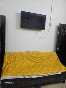 a bedroom with a bed with a tv on the wall at SYED Rest House in Karachi