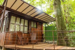 eine Hütte im Wald mit Stühlen auf einer Terrasse in der Unterkunft La Fortuna Natural Green in Fortuna