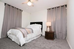 1 dormitorio con 1 cama y 1 mesa con lámpara en Tranquil Ranch Near Detroit & AA - Whole house with 2 bedrooms - Sleeps 6, en Westland