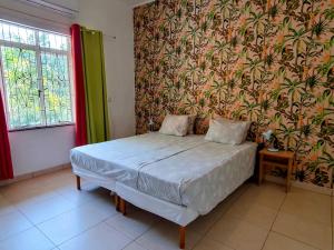 1 dormitorio con 1 cama en una habitación con papel pintado en Abaai Resort B&B, en Willemstad