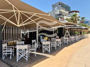 uma fila de mesas e cadeiras sob guarda-sóis numa praia em Sunny Moon 510 em Durrës