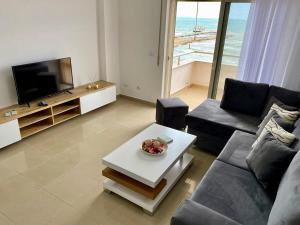 ein Wohnzimmer mit einem Sofa, einem TV und einem Tisch in der Unterkunft Costante 614 in Durrës