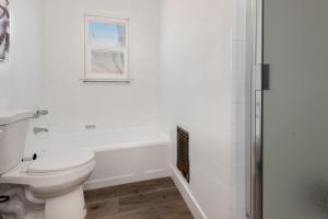 a white bathroom with a toilet and a bath tub at A Slice of Paradise: 2BR Apt. with Hot Tub in Los Angeles