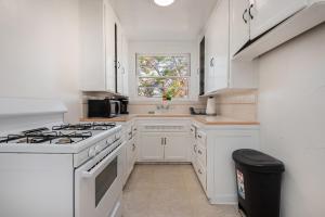 a white kitchen with a stove and a window at Modern Charming 1BR-Apartment with Hot Tub in Los Angeles