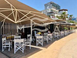 eine Reihe von Tischen und Stühlen unter Sonnenschirmen am Strand in der Unterkunft Nouveau 623 in Durrës