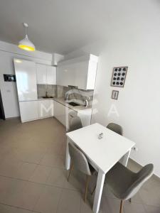 a white kitchen with a white table and chairs at Interstellar 830 in Durrës