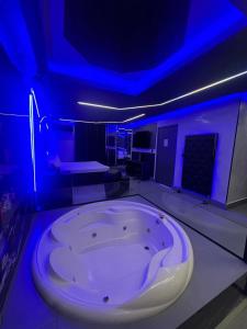 Prestige Motel 4 في سوروكابا: حوض أبيض كبير في غرفة مع أضواء زرقاء