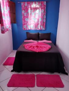 a bedroom with a black bed with pink rugs at Hostel Raio de Fogo in Paraty
