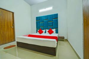 a bedroom with a bed with blue and red pillows at OYO H.S HOTEL in Bhopal