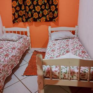 1 dormitorio con 2 camas y pared de color naranja en Hostel Raio de Fogo, en Paraty