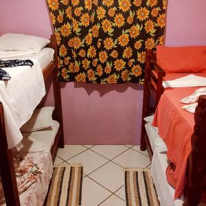 a room with two beds and a wall with a flowery wallpaper at Hostel Raio de Fogo in Paraty