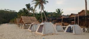 un grupo de tiendas de campaña en una playa de arena en Amwani Sunset Colours Camping Site, en San Vicente